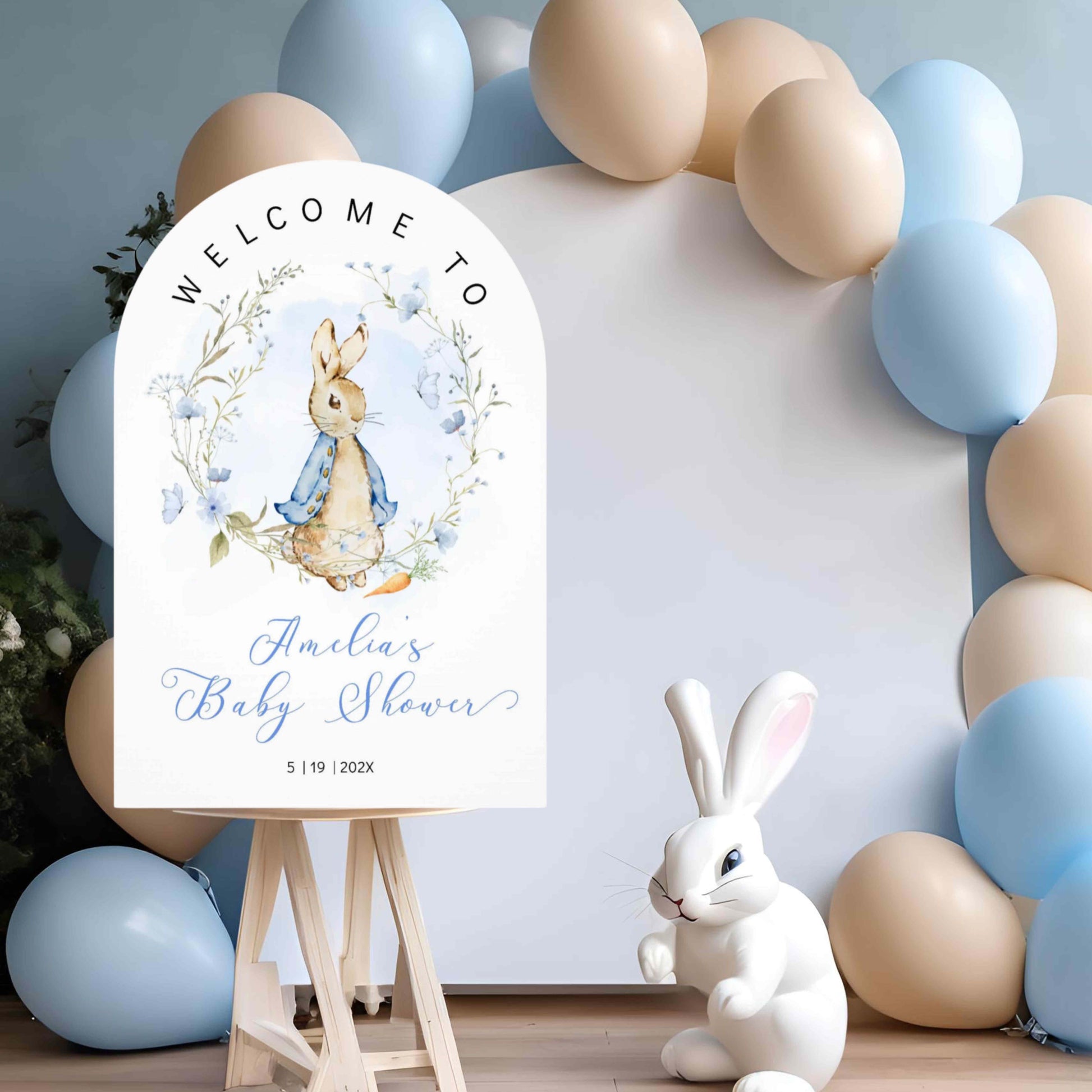 Baby shower welcome sign with Peter Rabbit design, surrounded by blue and beige balloons and flowers. Printed and Free Shipping. Arch Foam Board.