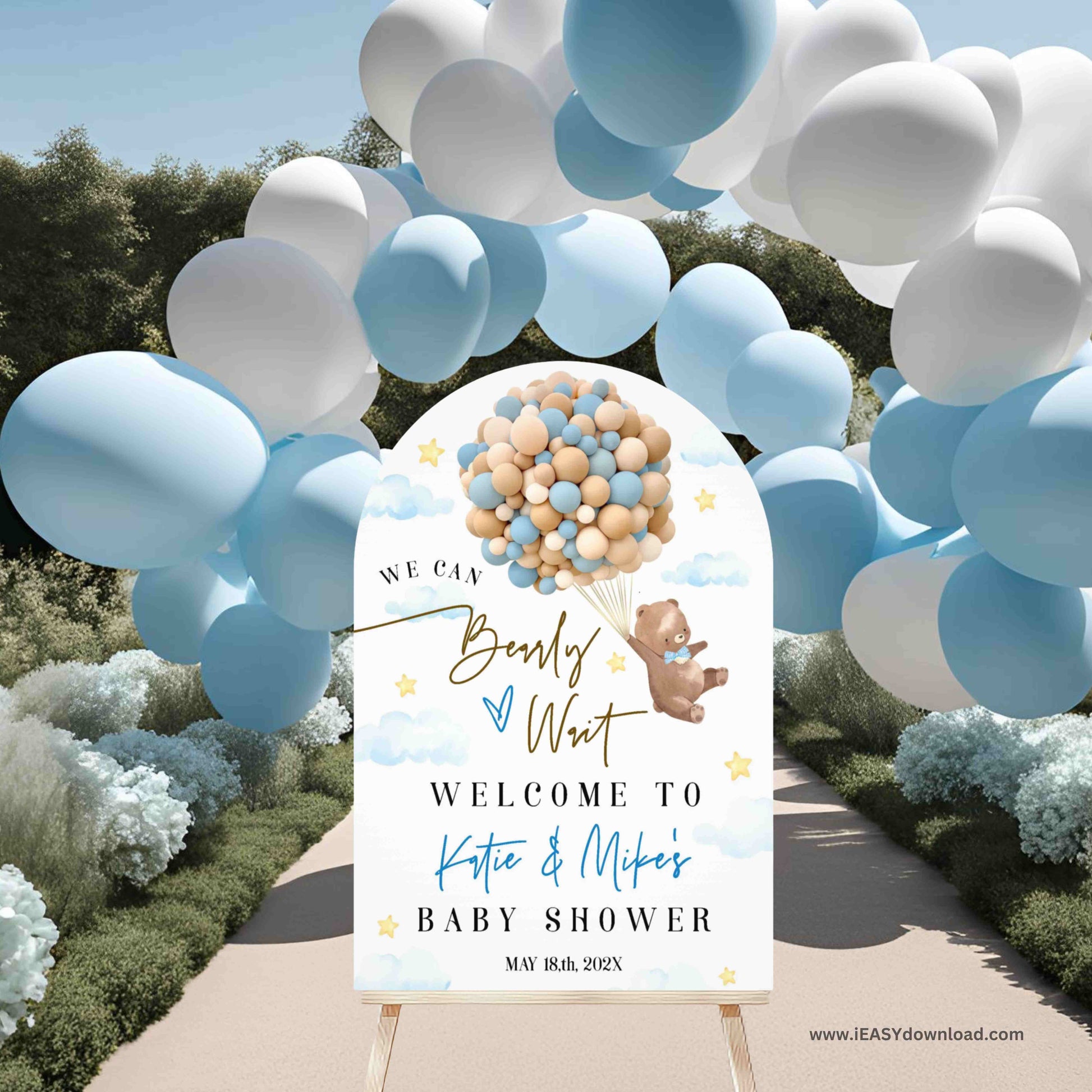 Baby shower welcome sign with balloons and teddy bear design, surrounded by blue and white balloons outdoors.