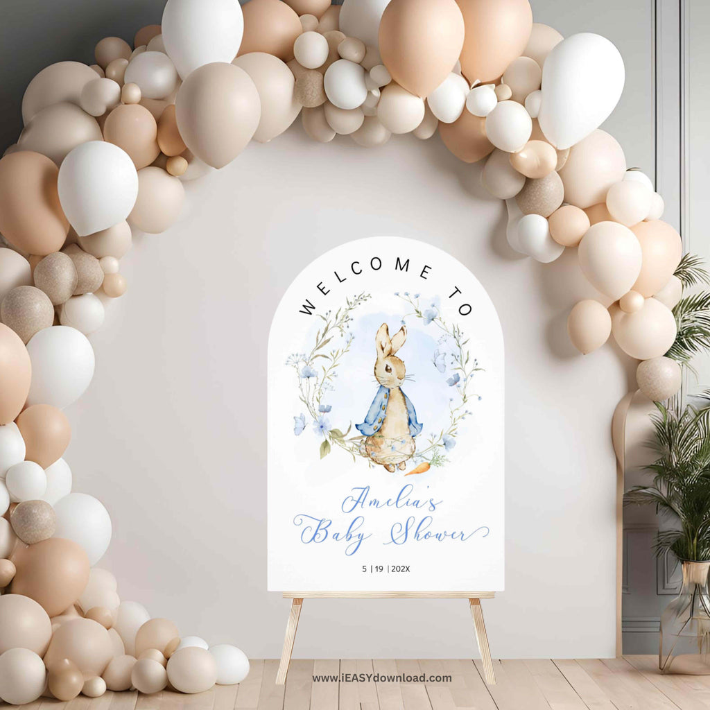 Baby shower welcome sign with Peter Rabbit design in front of a balloon arch.