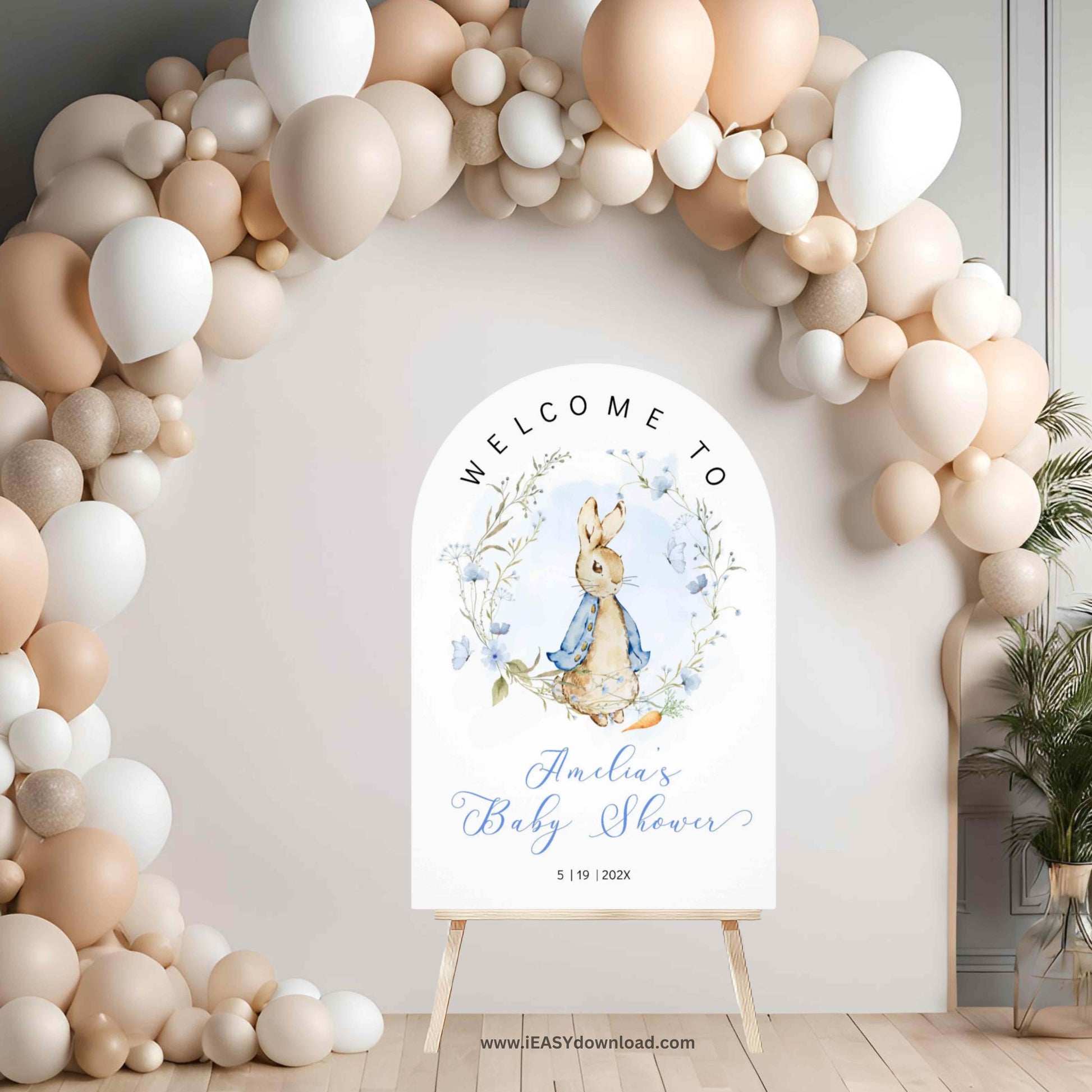 Baby shower welcome sign with Peter Rabbit design in front of a balloon arch.