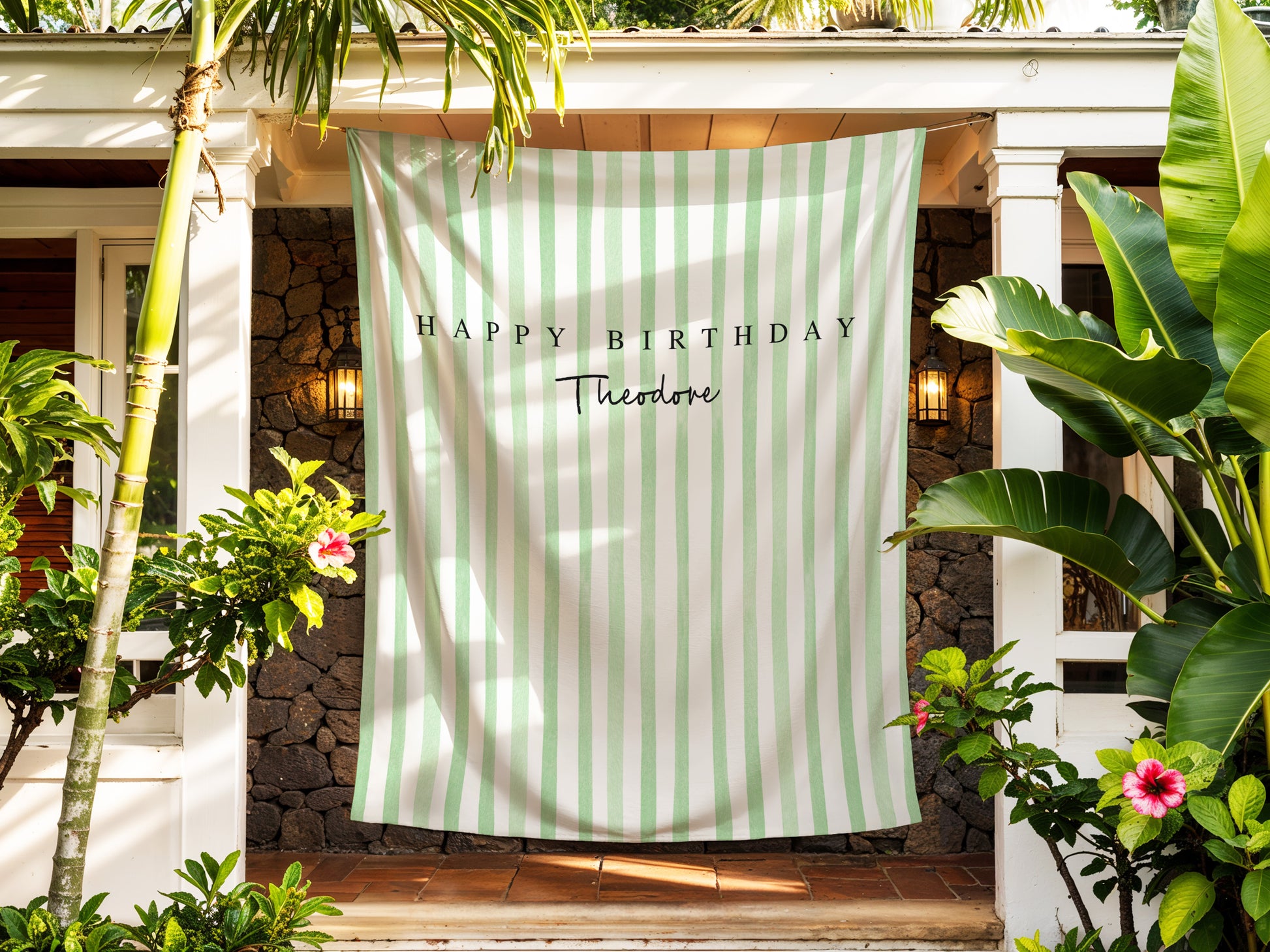 Green and white striped towel with 'Happy Birthday Theodore' text hanging outdoors.