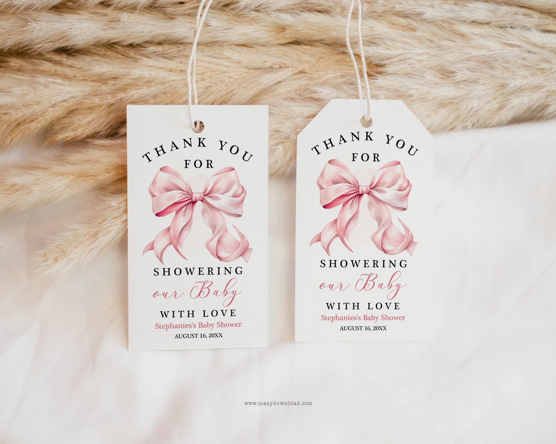 Two baby shower thank you tags with pink bows on a textured fabric background