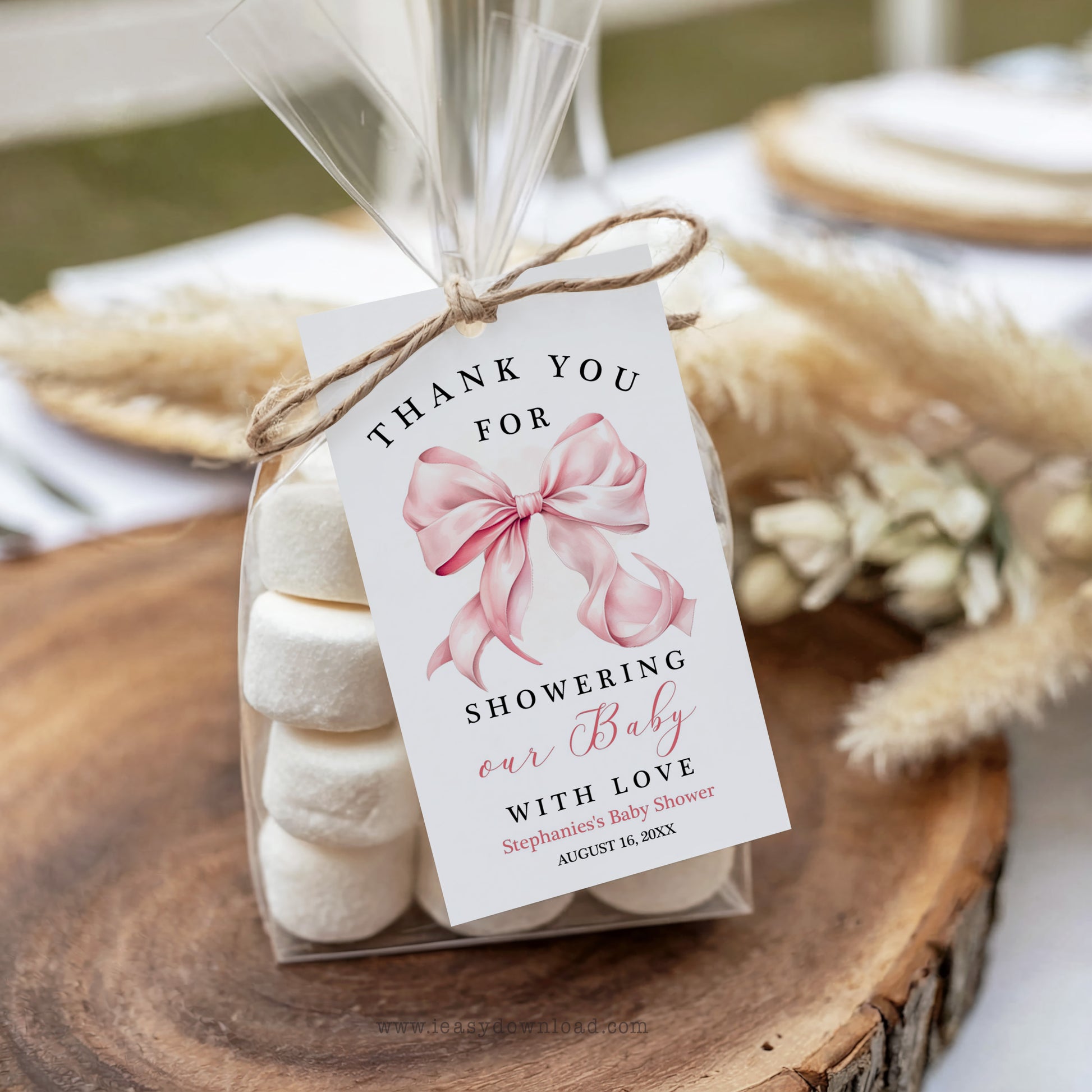 Baby shower favor with marshmallows and a pink bow on a wooden surface